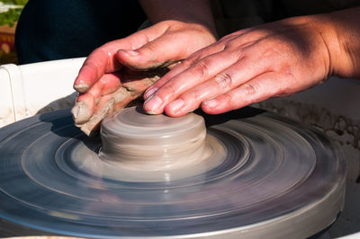 Cropped hands of man molding a shape on pottery wheel