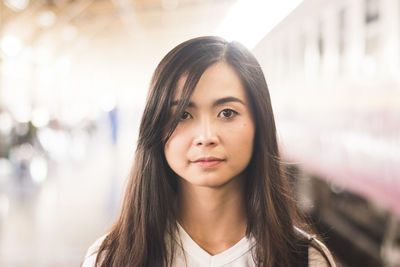 Portrait of young woman standing at railroad station platform