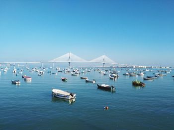 Boats moored in sea against clear blue sky