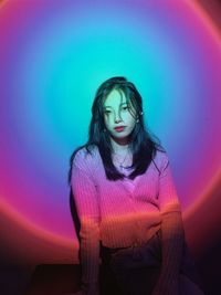 Portrait of young woman standing against wall