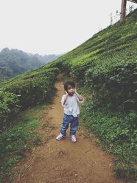 Full length of girl standing on field against mountain