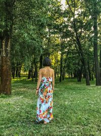 Rear view of woman standing on grass land in park