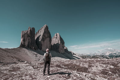 Man standing on rock against sky