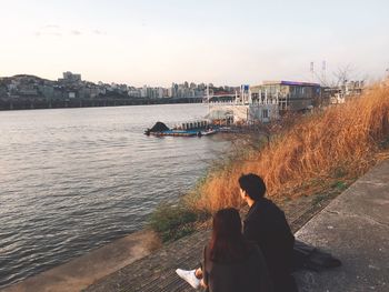 Rear view of man and woman on river against sky