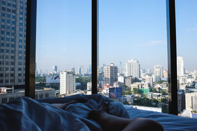Low section of woman on bed against cityscape