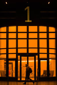 Rear view of silhouette man standing against orange building