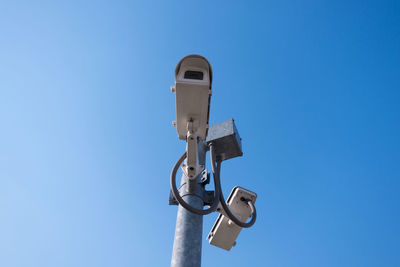 Close-up of security camera against clear blue sky