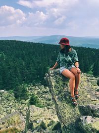 Full length of man sitting on rock against sky