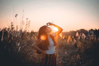 Woman standing on field against sky during sunset