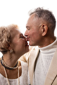 Side view of senior couple kissing against white background