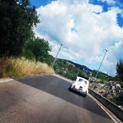 Cars on road against cloudy sky