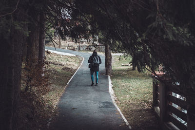 Rear view of women walking on footpath amidst trees