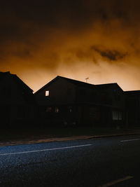 Road by buildings against sky at dusk