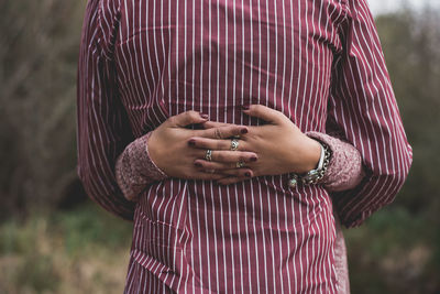 Cropped hands of woman embracing man while standing against trees