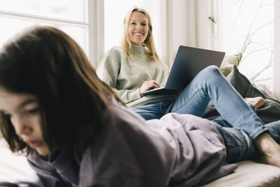 Portrait of smiling woman sitting with laptop by son at home