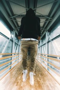 Rear view of a man walking on footbridge