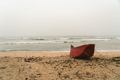 Boat moored on beach against sky