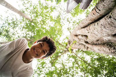 Portrait of a smiling young man sitting on tree trunk