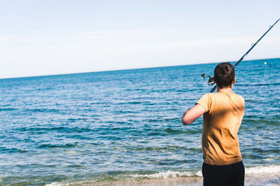 Rear view of man looking at sea against sky