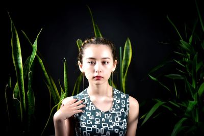 Portrait of a beautiful young woman standing against black background