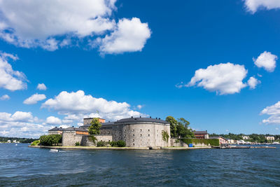 Buildings at waterfront against cloudy sky