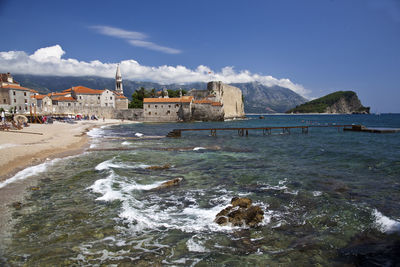 Scenic view of sea by buildings against sky
