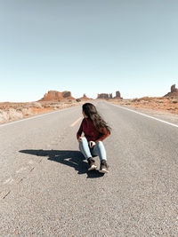 Side view of woman walking on beach against clear sky in monument valley