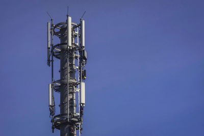 Low angle view of telephone pole against clear blue sky