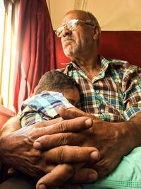 Low angle view of man with boy sitting by window