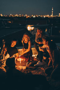 High angle view of friends enjoying rooftop party on illuminated terrace in candlelight