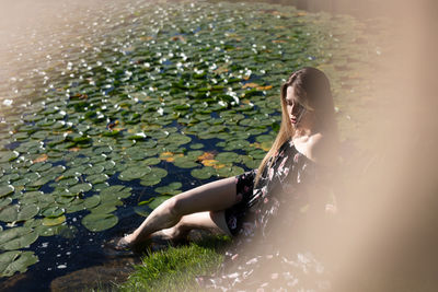 Full length of woman sitting by lake