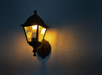 Low angle view of illuminated lamp mounted on wall