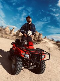 Man riding motorcycle on land against sky