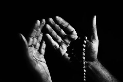 Close-up of hand on cross against black background