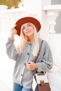 Portrait of young woman standing against wall