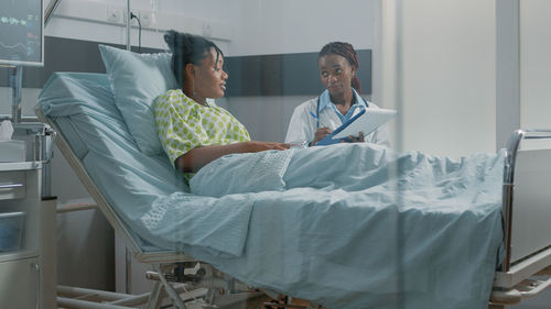 Young woman using laptop while sitting on bed