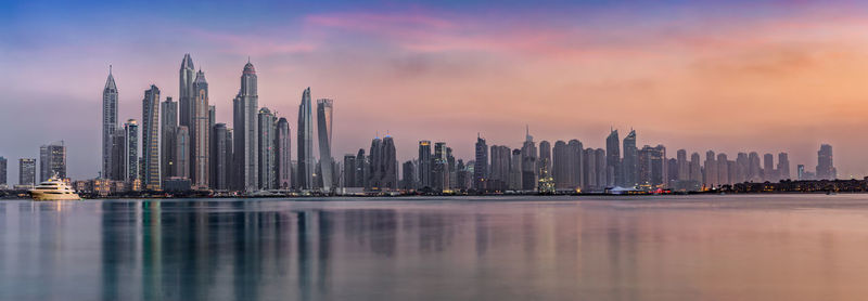 City at waterfront against cloudy sky