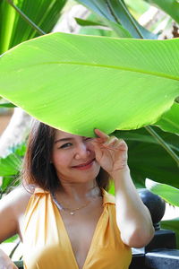 Portrait of smiling woman standing by banana leaf