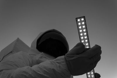 Low angle view of man holding illuminated built structure against sky