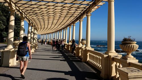 People walking on bridge by sea against sky