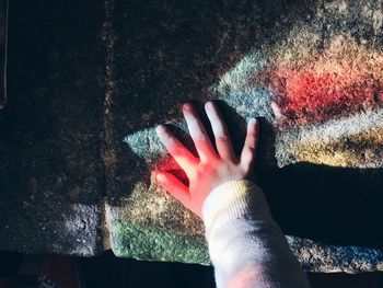 Cropped hand of girl touching weathered wall