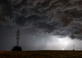 Electricity pylon on field against sky