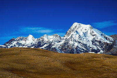 Scenic view of snowcapped mountains against blue sky