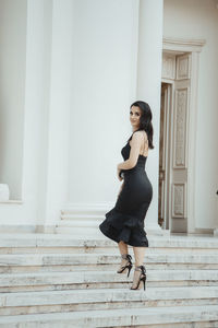 Portrait of young woman standing against staircase