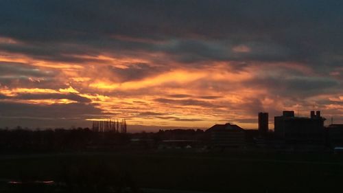 Silhouette buildings against dramatic sky during sunset