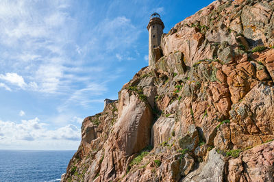 Low angle view of rock formation by sea against sky