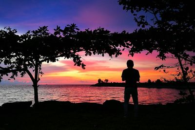 Silhouette man on beach against romantic sky at sunset