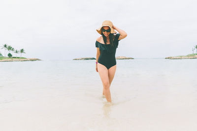 Full length of woman standing at beach against sky