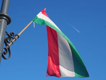 Low angle view of red flag against blue sky