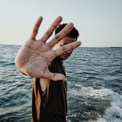 Close-up of hand holding sea against sky